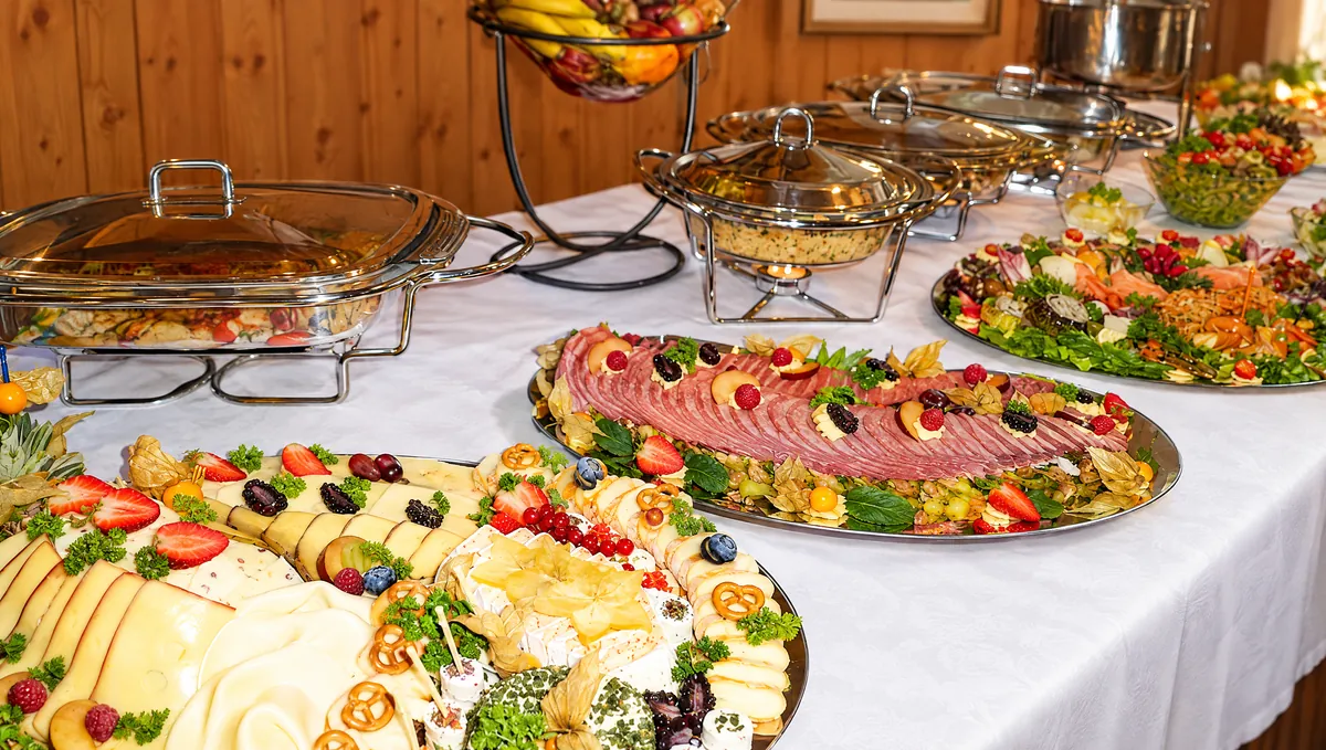 Festlich gedecktes Buffet mit Käse- und Wurstplatten und Warmhaltebehältern